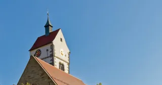 Sommerliche Szene mit einer Kirche in ländlicher Umgebung und offener, einladender Atmosphäre als Bildidee für eine Predigtreihe.