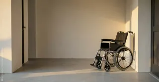 Eine ruhige Alltagsszene im warmen Licht: Eine Hand hält eine Tür offen. Der Bildraum ist schlicht und still. Das Motiv wirkt aufmerksam und einladend.